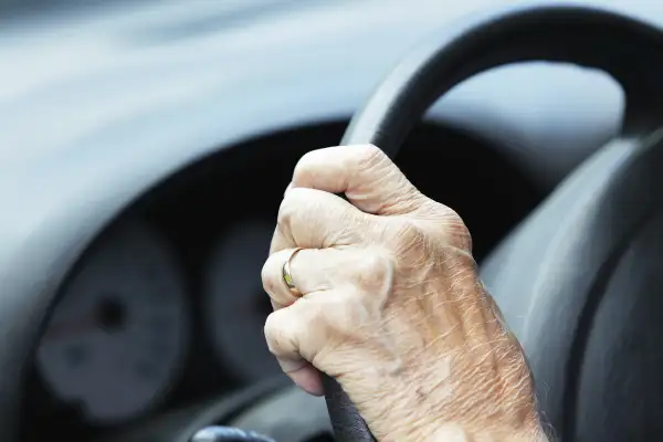 senior hand on steering wheel