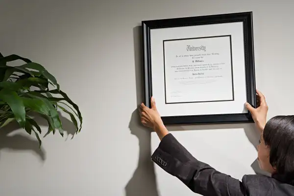 woman hanging diploma in office