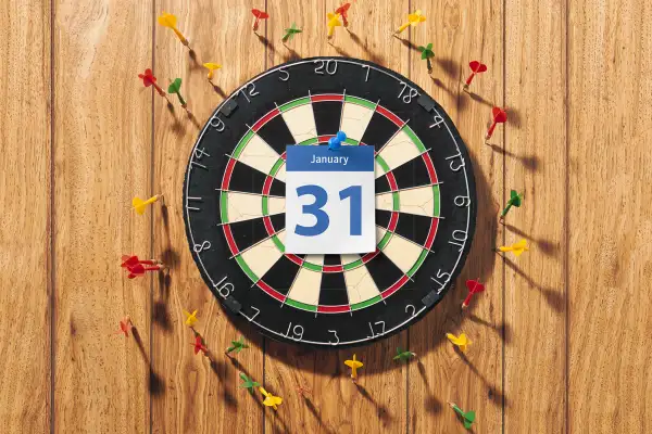 dartboard with January 31 calendar page in middle, dart boards hitting wall and missing target