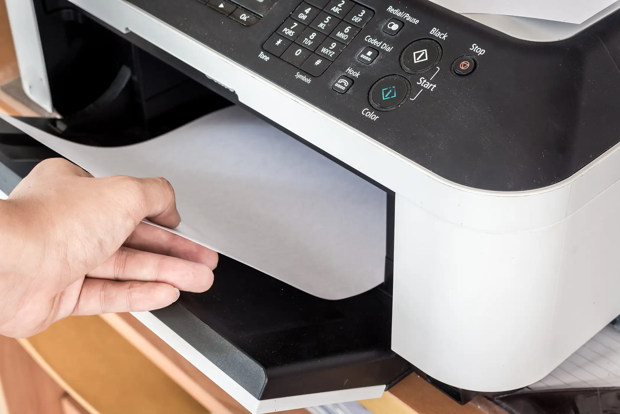 person putting paper in printer