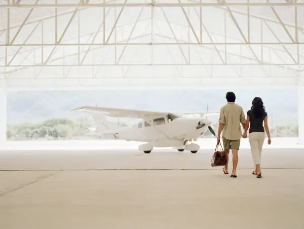 Young couple walking to private plane in hangar