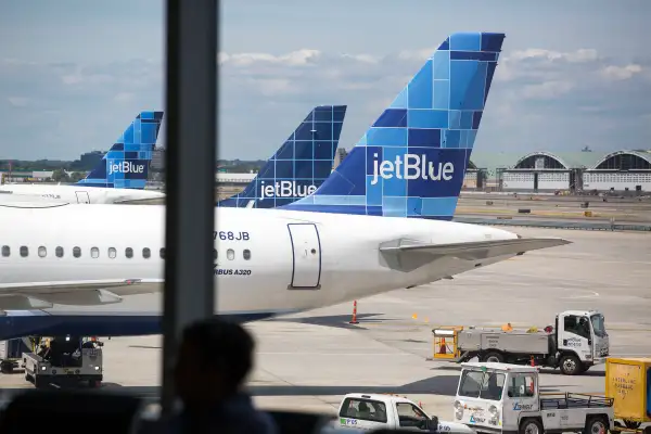 JetBlue Airways Corp. planes sit on the tarmac as a passenger waits in Terminal 5 at John F. Kennedy International Airport (JFK) airport in New York, U.S., on August 7, 2015.