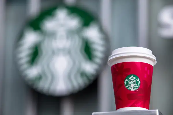A paper coffee cup and Starbucks logo.   Starbucks will