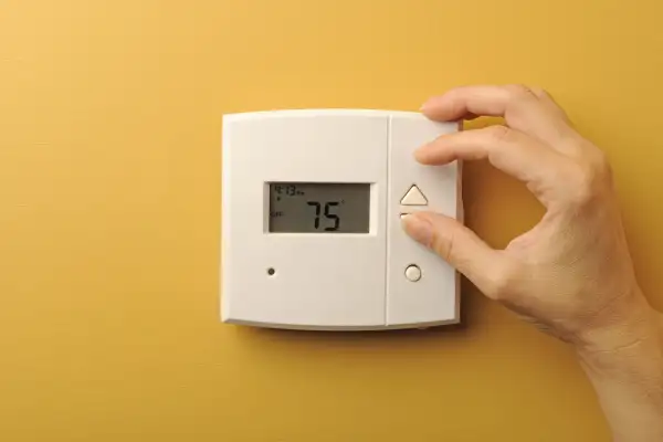 person adjusting thermostat