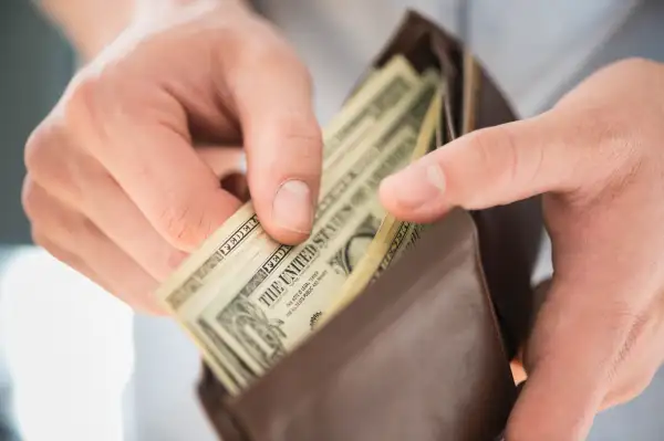 Young man holding wallet and counting money, Jersey City, New Jersey, USA