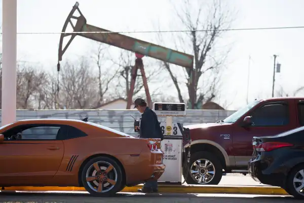A motorist fills his car with gas at a gas station near an oil field pumping rig in Oklahoma City, Feb. 12, 2016.