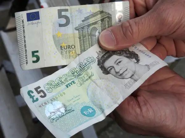 A 5-pound (bottom) and a 5-euro bill are held up in London, Britain, 24 June 2016. In a referendum on 23 June, Britons have voted by a narrow margin to leave the European Union (EU).