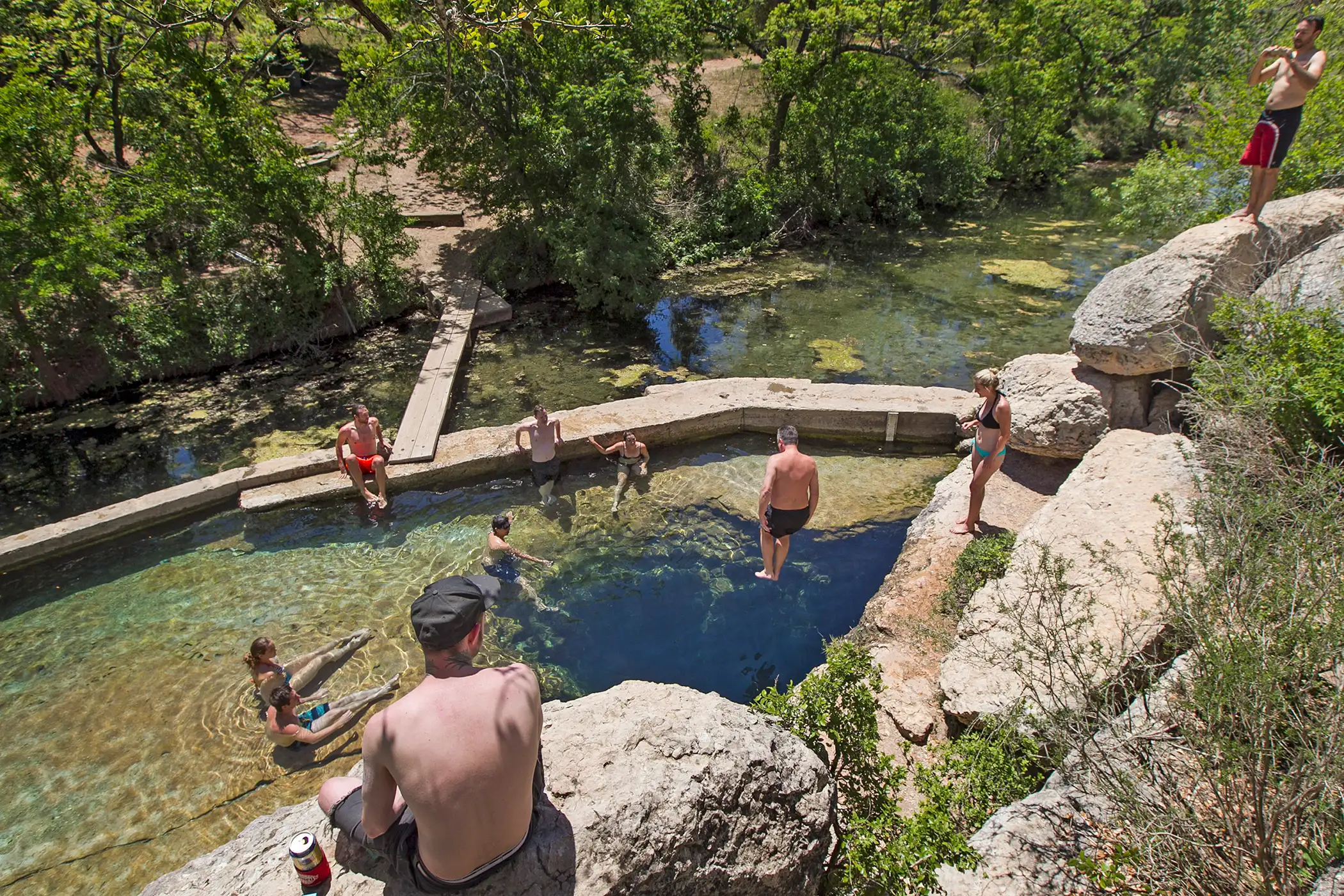 Visitors to Hays County's Jacob's Well Natural Area look on as a man leaps from the bluffs, aiming for the 12-foot cave opening though it is against park rules, in Wimberley, Texas, on Wednesday, April 30, 2014.