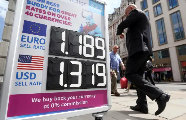 A pedestrian passes a sign advertising euro and U.S. dollar exchange rates outside a foreign currency exchange bureau in London, U.K., on Tuesday, June 28, 2016. The pound rose for the first time since the U.K.s vote to leave the European Union, as a recovery in investor appetite for higher-yielding assets seeped through currency markets.