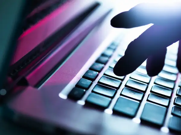 Close up of silhouetted male hand typing on laptop keyboard