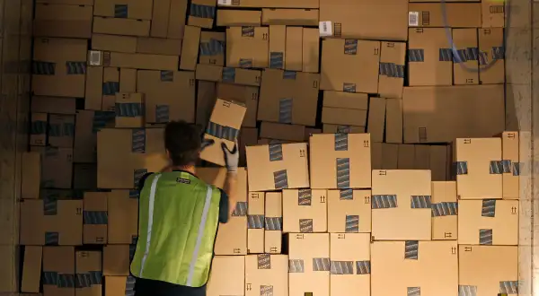 A worker stacks a shipping trailer with boxed items for delivery at Amazon's distribution center in Phoenix, Arizona November 22, 2013.