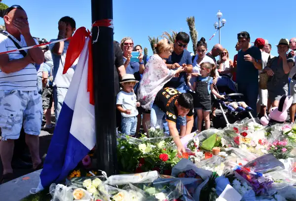 People visit the scene and lay tributes to the victims of a terror attack on the Promenade des Anglais on July 15, 2016 in Nice, France. A French-Tunisian attacker killed 84 people as he drove a lorry through crowds, gathered to watch a firework display during Bastille Day celebrations.
