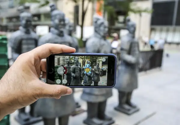 People take photo of the Terra Cotta warriors replicas in Chicago, United States on July 14, 016 as Pokemon go game is seen on a screen of a phone. Chicago Field Museum has created its own treasure hunt game while many are obsessed with Pokemon game. The museum began giving out clues on social media about the spots in Chicago to see life-size replicas of the terra cotta statues. The treasure hunt is a promotion for the Field Museum's special exhibit  China's First Emperor and His Terracotta Warriors,  where some of the original terra cotta figures and two painted replicas are on display.