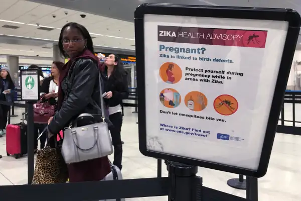 A woman looks at a Center for Disease Control (CDC) health advisory sign about the dangers of the Zika virus as she lines up for a security screening at Miami International Airport in Miami, Florida, May 23, 2016.