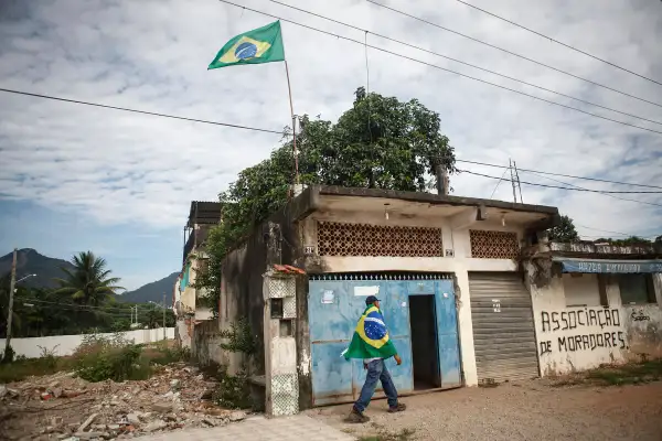 A resident walks while wearing a Brazilian flag in the mostly demolished Vila Autodromo favela community on February 24, 2016 in Rio de Janeiro, Brazil. Most residents of the favela community have moved out and had their properties demolished after receiving compensation for their homes which are located directly adjacent to the Olympic Park under construction for the Rio 2016 Olympic Games. A small fraction of remaining families from an original 700 or so in Vila Autodromo are resisting the controversial evictions and remain in the community. The favela sprang from an old fishing community and was considered one of the city's safest. Removals and demolitions have occurred in other Rio communities with tangential links to the games.
