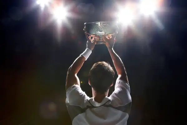 man holding trophy from rear, backlit