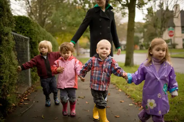 babysitter walking with four kids in daisy chain
