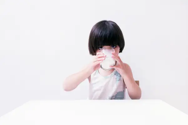 young child drinking glass of milk