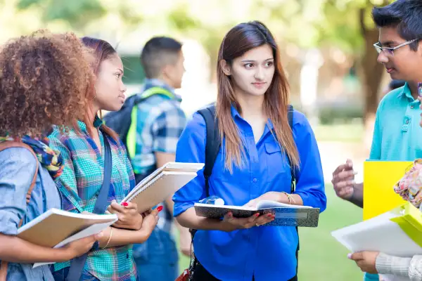 Diverse group of college students talking on campus lawn