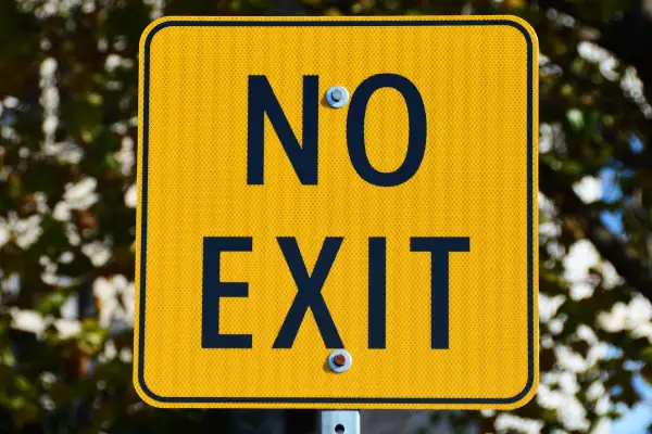 A rectangular gold sign with black lettering says no exit,no way out.
