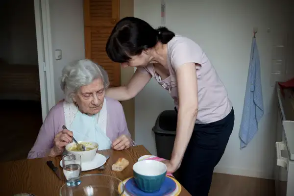 woman helping elderly woman eat