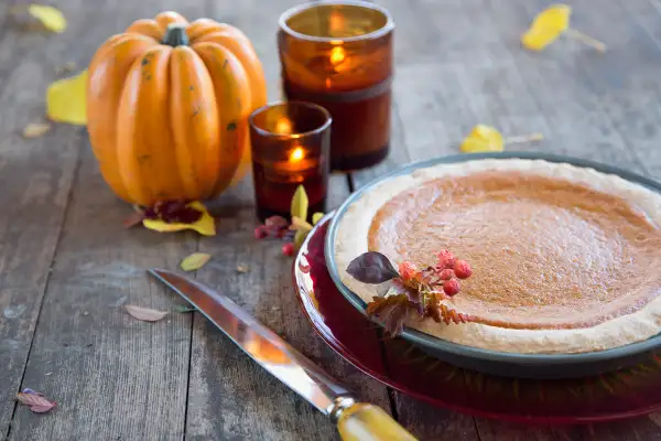 Pumpkin decoration with candles next to pumpkin pie