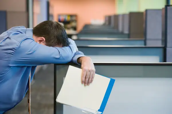 Businessman leaning head on cubicle wall