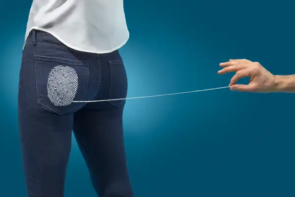 hand pulling thread of jeans to remove fingerprint design on back pocket