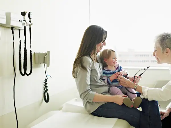 Mother holding daughter in exam room