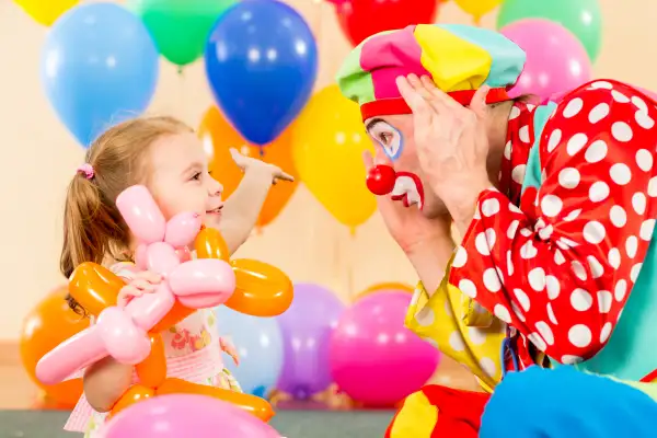 happy child girl and clown playing on birthday party