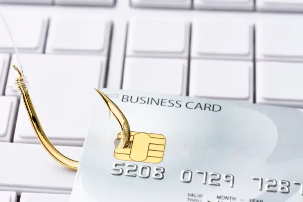 Close-up of credit card with fishing hook on computer keyboard