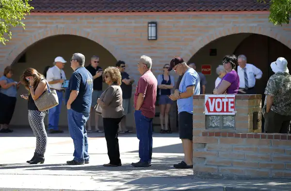 In this March 22, 2016 photo, voters wait in line to cast their ballot in Arizona's presidential primary election in Gilbert, Ariz. New ID requirements.