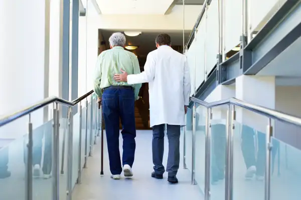 senior and doctor walking up hallway in hospital