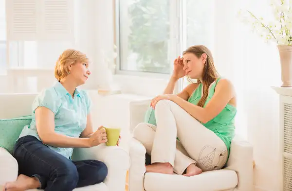 Mother and adult daughter sitting on sofa and talking