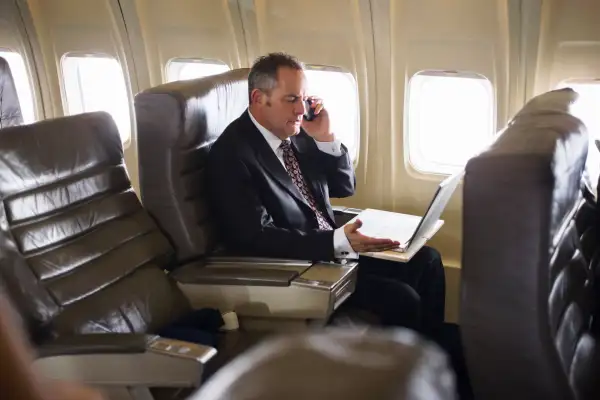 man wearing suit using cell phone on airplane