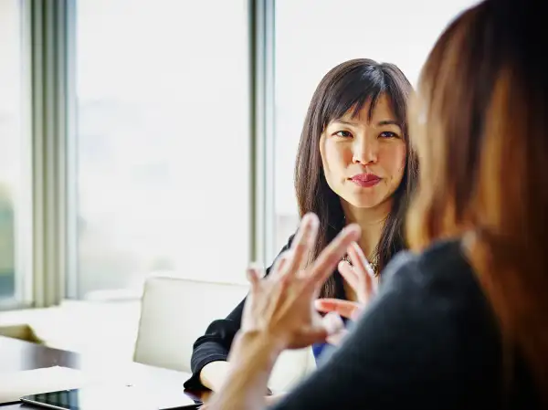 Two businesswomen discussing project details at table in conference room