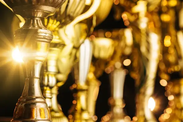 Group of the golden trophies in sparkling light on the dark background.