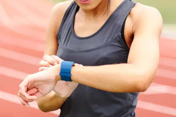 Young woman on running track, checking watch