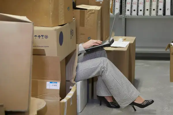 woman on laptop hiding in storage room