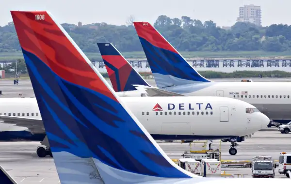 A Delta Air Lines plane taxis toward a gate between other De