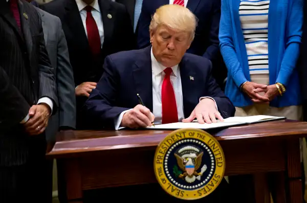 President Donald Trump signs an executive order in the Roosevelt Room at The White House on April 28, 2017 in Washington, D.C.