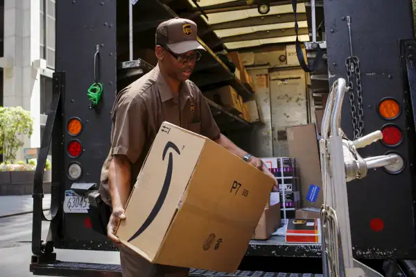 Worker carries an Amazon box to be delivered in New York