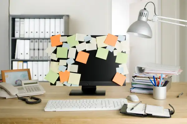 A desktop PC with blank adhesive notes all over the monitor