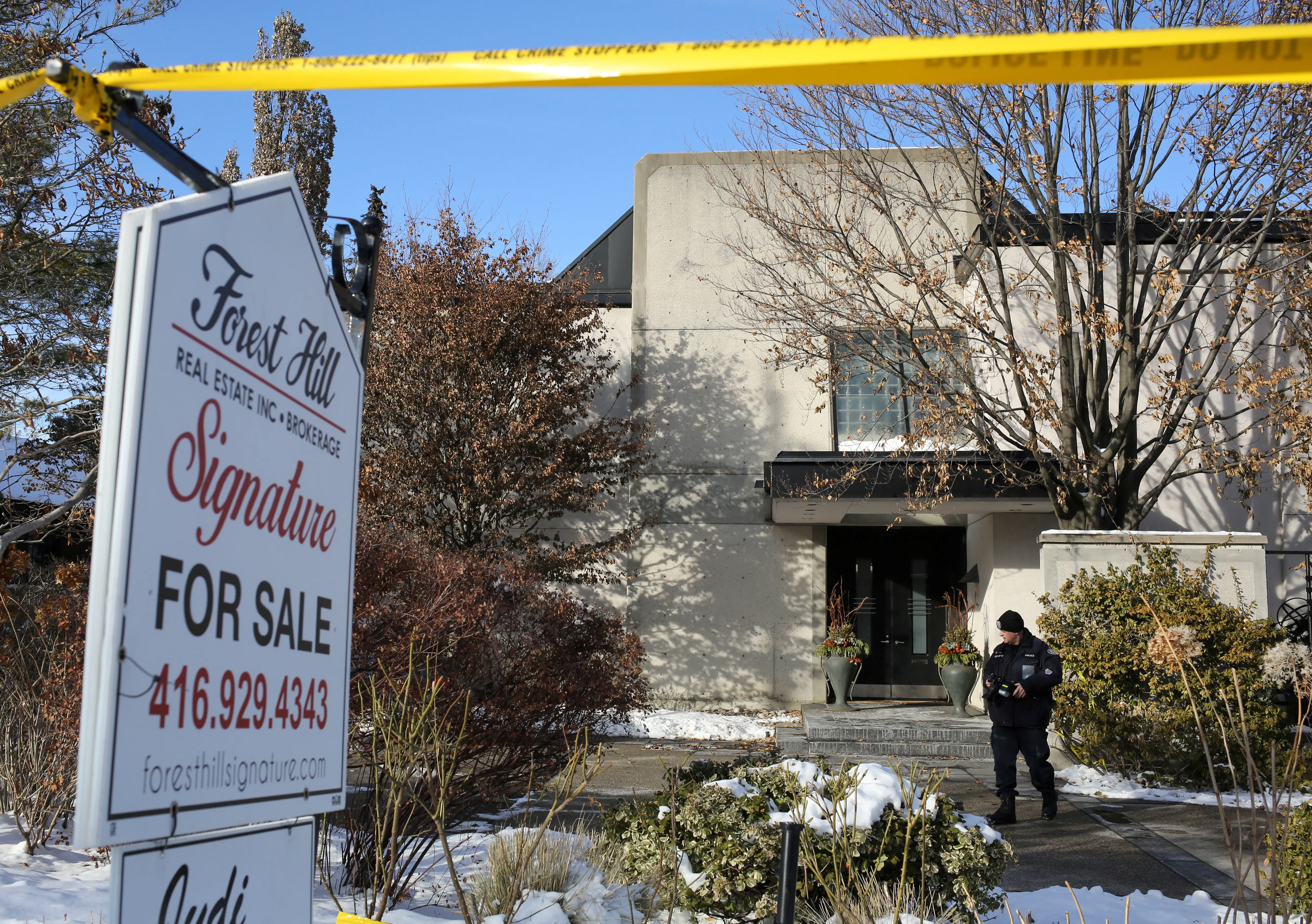 A police forensics photographer works outside the home of billionaire founder of Canadian pharmaceutical firm Apotex Inc. in Toronto