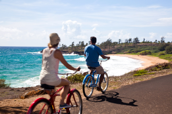 Couple ride on oceanside path. Kapaa Kauai County.