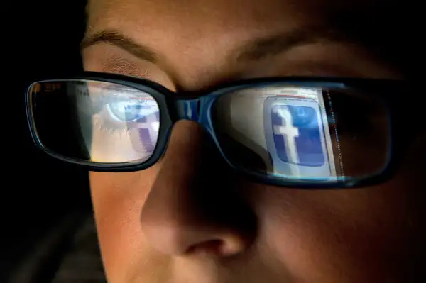 Woman with Facebook logo reflecting in glasses