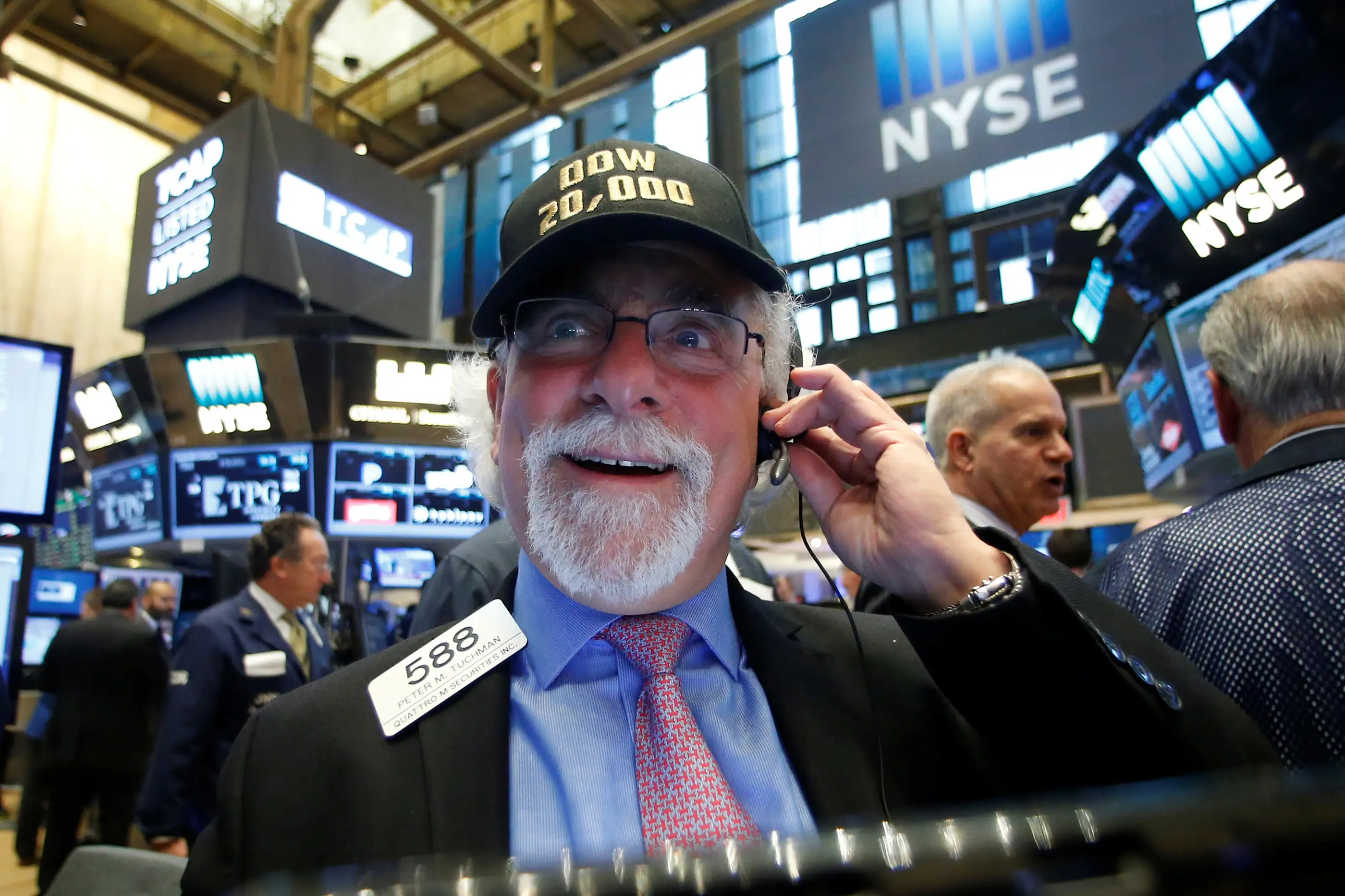 A trader works on the floor of the NYSE as the Dow Jones Industrial Average passes the 20,000 mark in New York