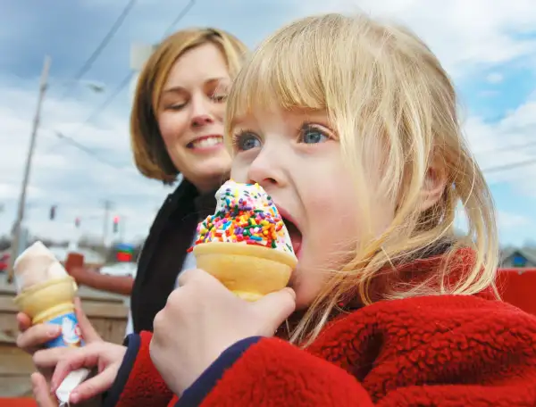 Three year old Emma Letarte enjoys her first jimmy coated ice cream cone of the year with her mother