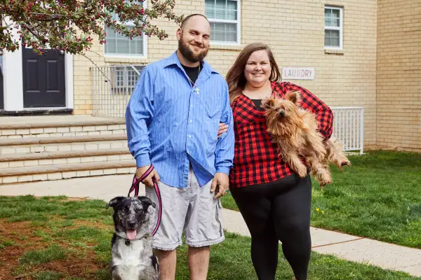 susskinds standing outside an apartment building with their two dogs