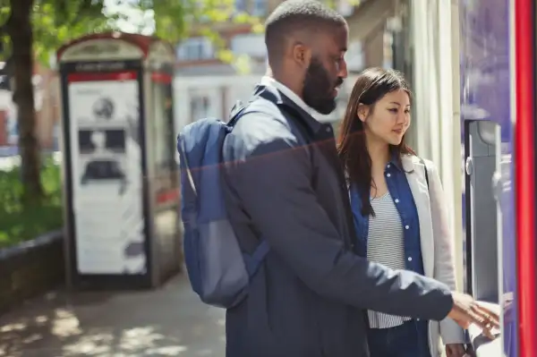 Young couple using urban ATM